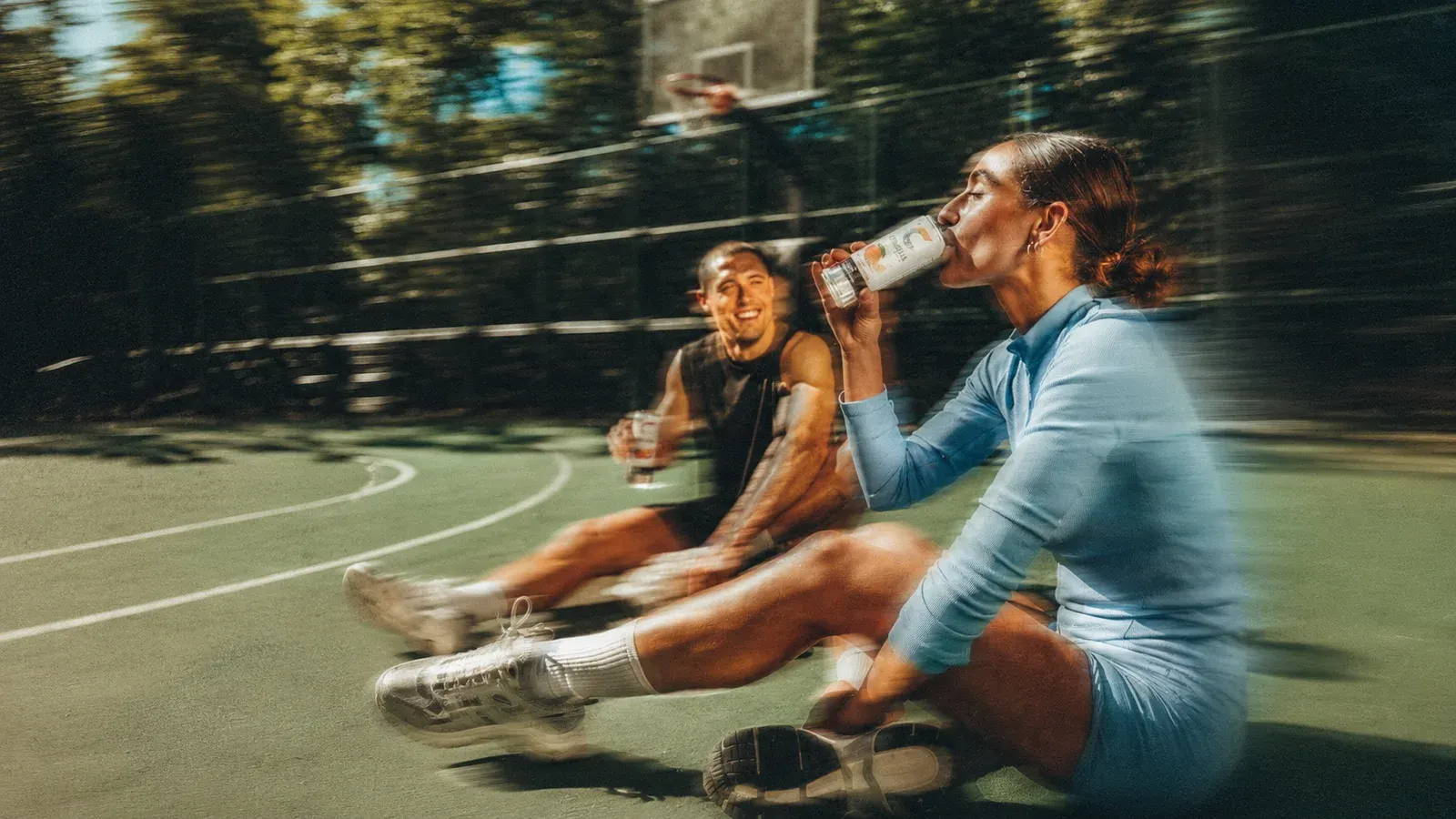 Dos personas descansando en una cancha después de entrenar
