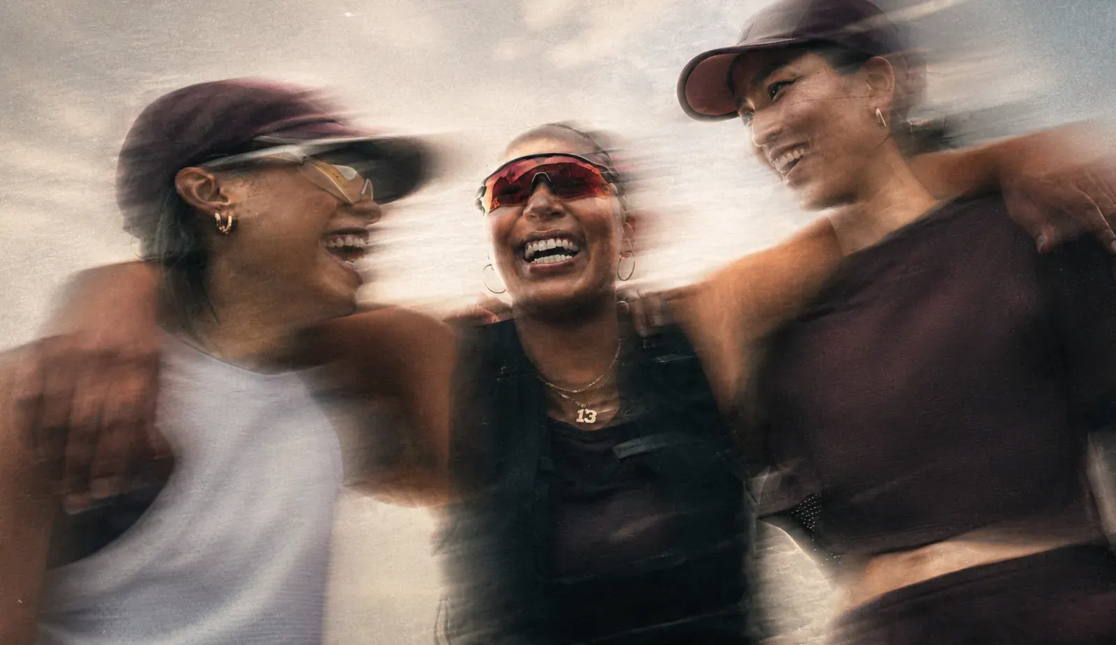 Tres amigas abrazadas y riendo después de entrenar
